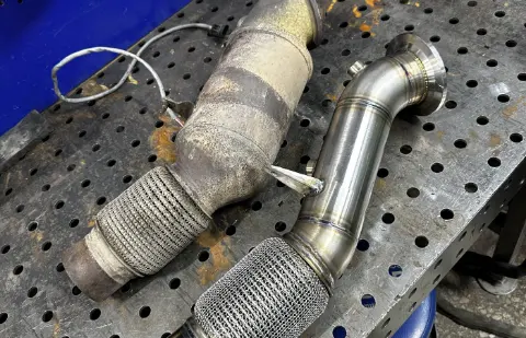 Новый downpipe BMW рядом со штатной деталью